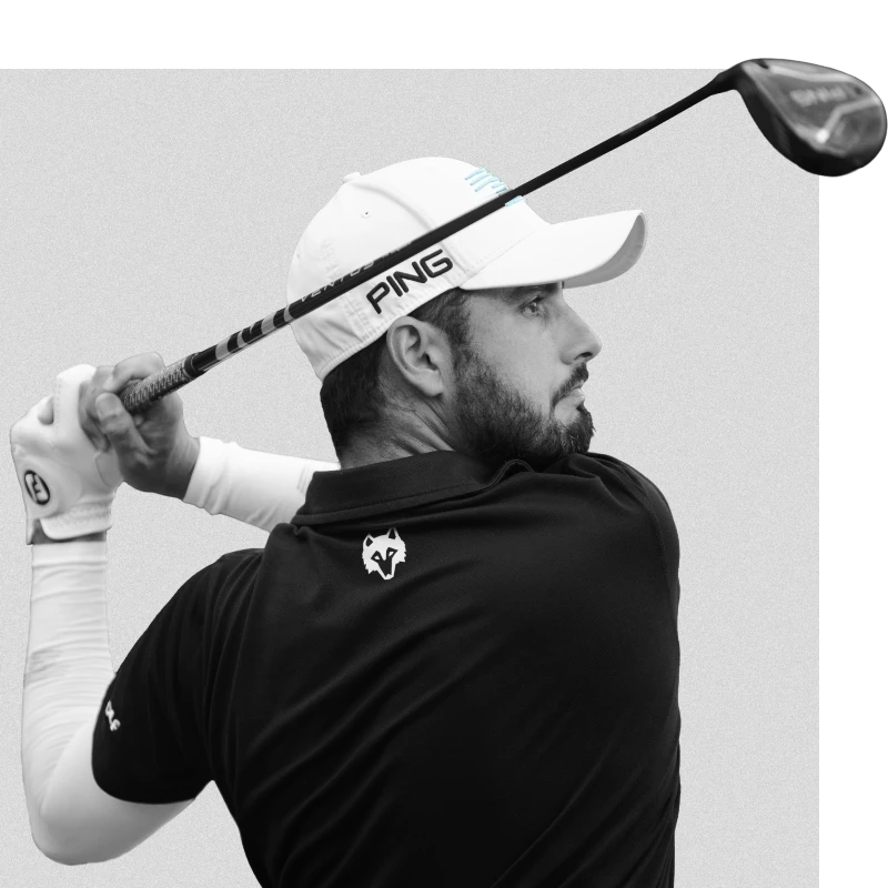 Man in a white cap and black shirt swings a golf club, focusing intently on his shot.