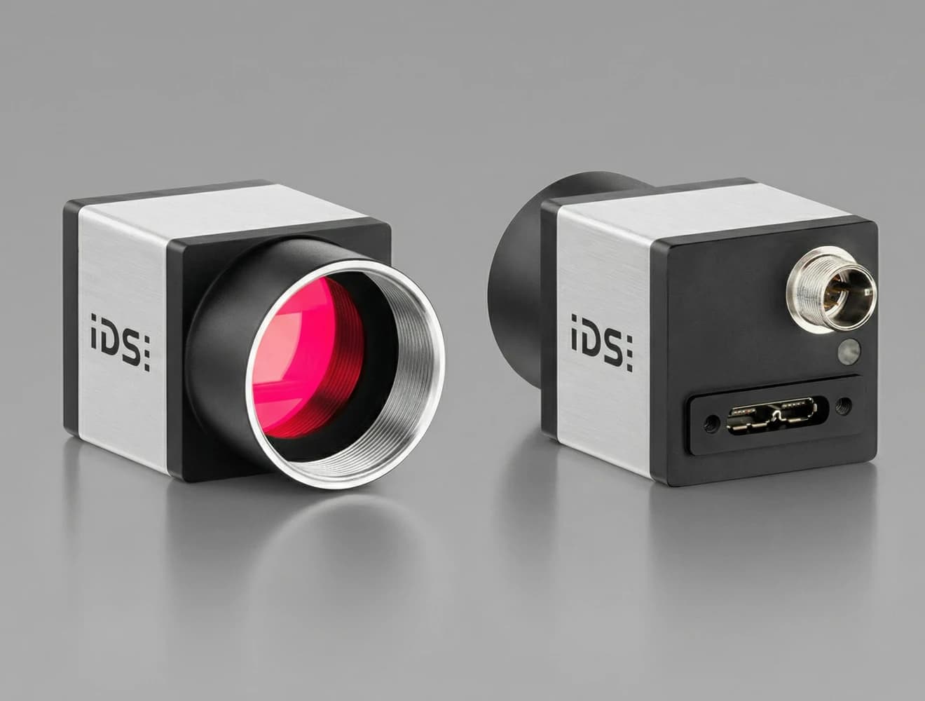 Two compact industrial cameras with silver and black casing, red-lensed front, and ports on the back, both labeled "iDS:" on a gray background.