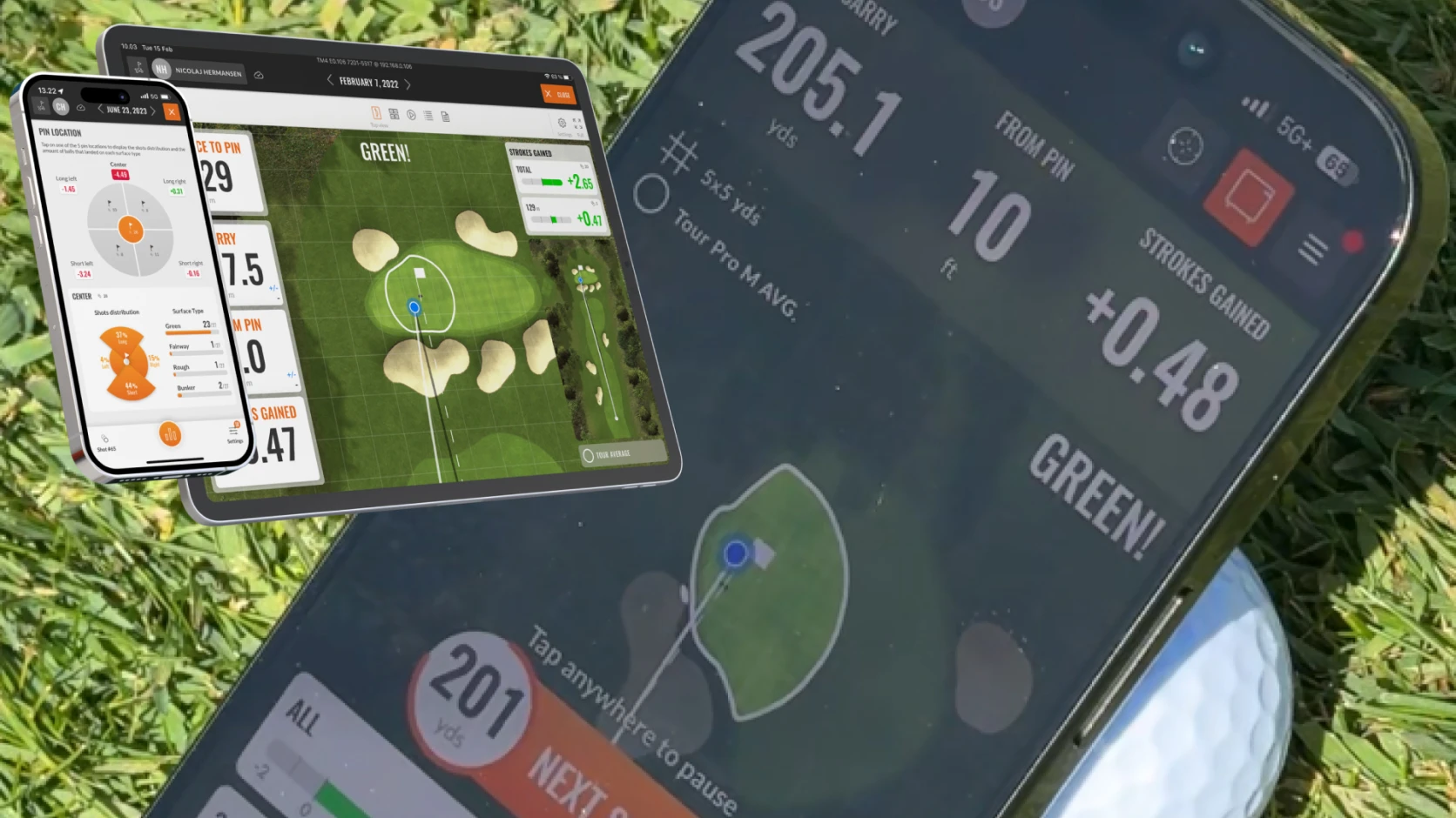 Smartphone displaying a golf app showing course layout, distance, and stats. The device is on grass with a golf ball partially visible.
