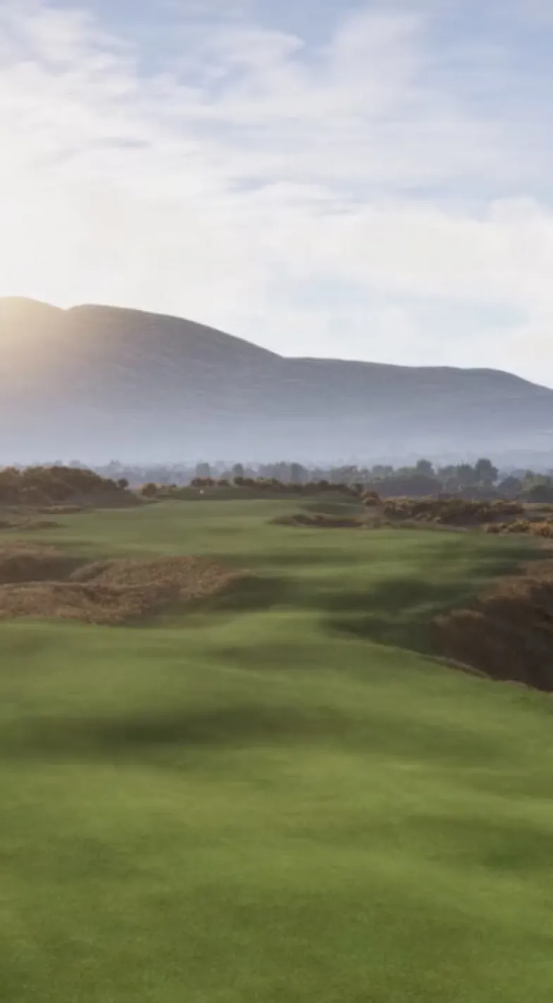 Sunlit golf course with rolling green fairway, distant hills, and a clear blue sky.